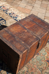 Antique wooden trunk's wide plank top with a rich patina and rustic metal bands.