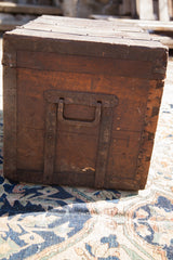 Patinated iron handle and riveted metal straps on an antique wooden trunk's side.