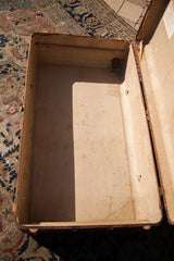 Open vintage trunk interior showing light spotting, discoloration, and metal hardware.