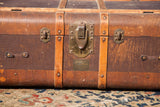 Vintage Indestructo Trunk's brass latch, brand plate, and aged wood straps.