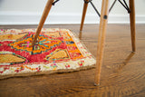 Whimsical plush deep red Turkish rug edge showing orange motifs and colorful cream fringe.