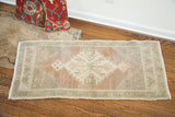 Blanched Turkish runner corner with pastel geometric border and plush pile.