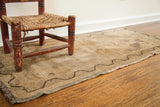 Faded tan vintage Turkish rug runner with dark meandering border and fringed end.