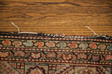 Worn edge detail of an antique Feraghan rug, featuring red, blue, and tan border motifs.