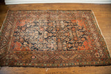 Antique Feraghan rug with navy and terracotta tones, showcasing its worn Herati motif.