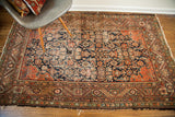 Aged bottom corner of the antique Feraghan rug, showing worn edge and classic Herati motif.