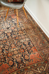 Worn antique Feraghan rug corner featuring Herati motif, faded orange, navy, and spandrels.