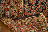 Antique Feraghan rug's storied Herati motif, time-softened pile, and visible woven edge.
