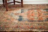 Antique tribal rug's worn texture, showcasing earthy red, blue geometric patterns, and exposed foundation.