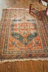 Geometric patterns, worn pile, tattered fringe of antique tribal rug in orange and blue.