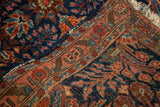 Tattered edge and ornate coral floral border of the deep blue Sarouk rug.