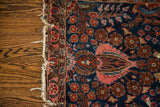 Tattered edge detail of the deep blue Sarouk rug, with ornate red and pink florals.