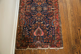 Deep blue field of a vintage Sarouk runner with ornate floral patterns and a distinctive tattered fringe.