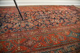 Visible wear on saturated blue herati pattern and geometric red border of vintage Kurdish rug.