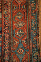 Kurdish runner detail: rust-red and blue geometric herati motifs with textured wear, tattered edge.
