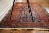 Worn fringe and detailed herati pattern on the antique blue Kurdish runner rug's red border.