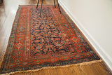 Antique Kurdish runner with deep blue herati pattern, red borders, and visible wear.