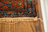 Tattered fringe, exposed foundation, and blue geometric motifs on a vintage Kurdish rug end.