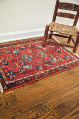 Diminutive vintage Persian rug with brilliant cherry red field and detailed floral border.