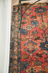 Detailed patterns of the red Lilihan Sarouk rug with worn blue geometric border.