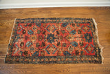 Textured red pile, blue motifs, and tattered edge of the Lilihan Sarouk rug corner.