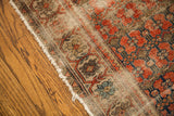 Worn antique rug's unusual repeating floral design, abrash tones, and frayed edge.