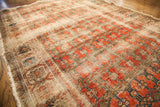 Worn and tattered texture of the antique rug, revealing faded red floral motifs.