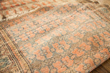 Antique rug's unusual repeating coral floral design with muted blue details and visible abrash.