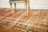 Antique worn rug's tattered edges and faded coral repeating floral design with abrash.