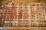 Worn corner of antique rug, featuring faded floral patterns, abrash, and tattered fringe.