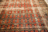 Detail of antique rug's unusual repeating red, navy floral motifs and worn abrash texture.