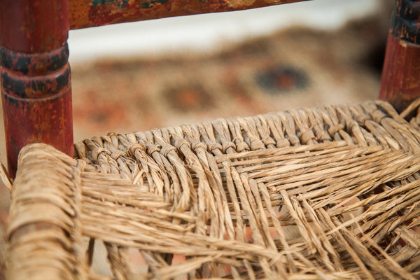 Worn and woven rush seat texture on a hand-painted primitive chair.