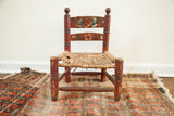 Antique folk art child's chair with a chippy red finish and hand-woven rush seat.