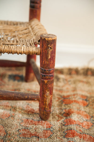 Hand-carved leg of a folk art chair with a chippy, painted red and blue finish.