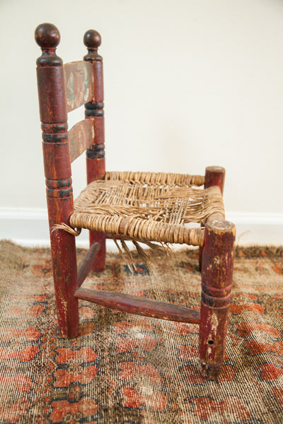 Worn hand-woven rush seat and chippy red painted leg on the antique folk art chair.