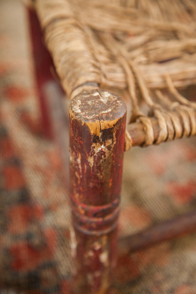 Close-up of a chair leg's worn wooden top and chippy red painted finish.