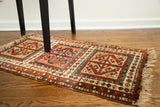 Bold geometric design on antique Caucasian rug, terracotta, cream, and muted blue tones.