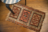 Antique Caucasian rug with storied geometric patterns in rich terracotta, deep red, and muted blue.