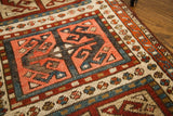 Tribal geometric pattern on an antique Caucasian rug with salmon, indigo, and cream.