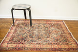 Antique Lavar Kerman rug detail, highlighting distressed central medallion and delicate floral motifs.