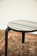 Alvar Aalto-style side table with beige striped top and chipped black edge.