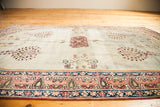 Ornate pink and blue curvilinear border on a sea foam green Antique Laver Kerman.