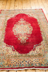 Ornate floral border, fringe, and rich cochineal red field of a vintage Kerman rug.