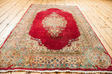 Curvilinear floral border detail of the Cyrus Crown Kerman rug, with ruby red, beige, and teal motifs.