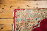 Ornate curvilinear floral motifs on the plush red field of this vintage Kerman rug corner.