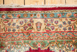 Cyrus Crown Kerman rug border with insignia, cochineal red, teal, and ivory floral patterns.