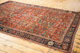 Antique Fereghan rug corner featuring saturated greens, golds, blues, and earth tone rust ground.
