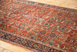Intricate floral pattern in saturated green, gold, and blue on the rust Fereghan carpet.
