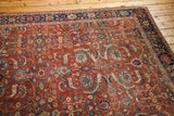 Corner of an antique Fereghan carpet: rust ground, curvilinear floral pattern, saturated blues and greens.