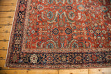 Antique Fereghan rug corner: dark blue border framing a rust field of vibrant floral motifs.
